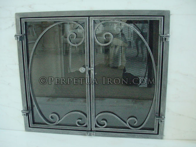 Ornamental iron fireplace screen with mesh doors.